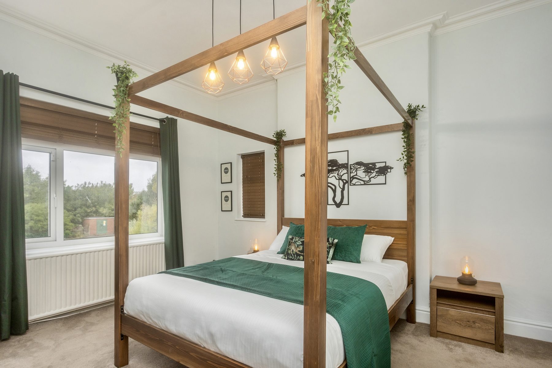 The Deluxe King room, with a wooden four-poster bed and green throw.