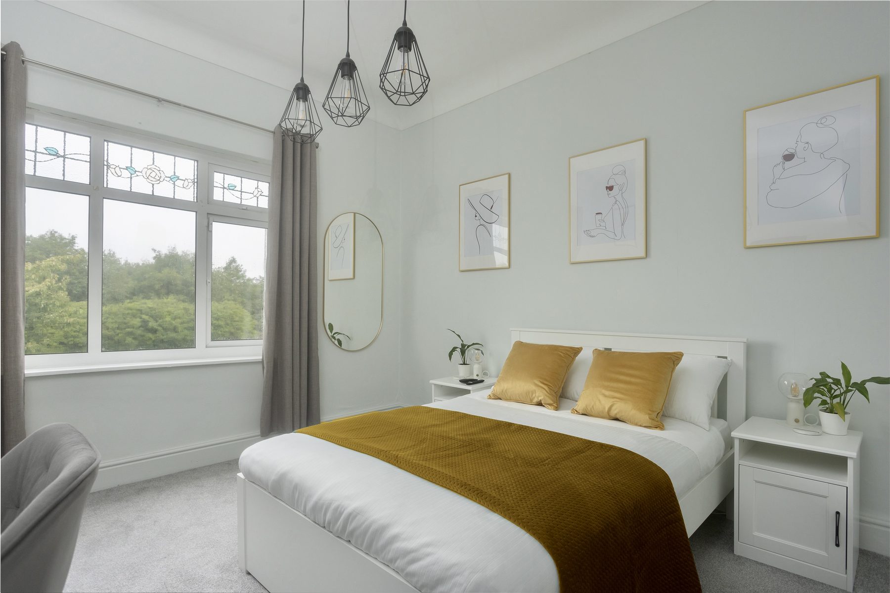 The Deluxe Double room, with a mustard throw and pendant lighting.